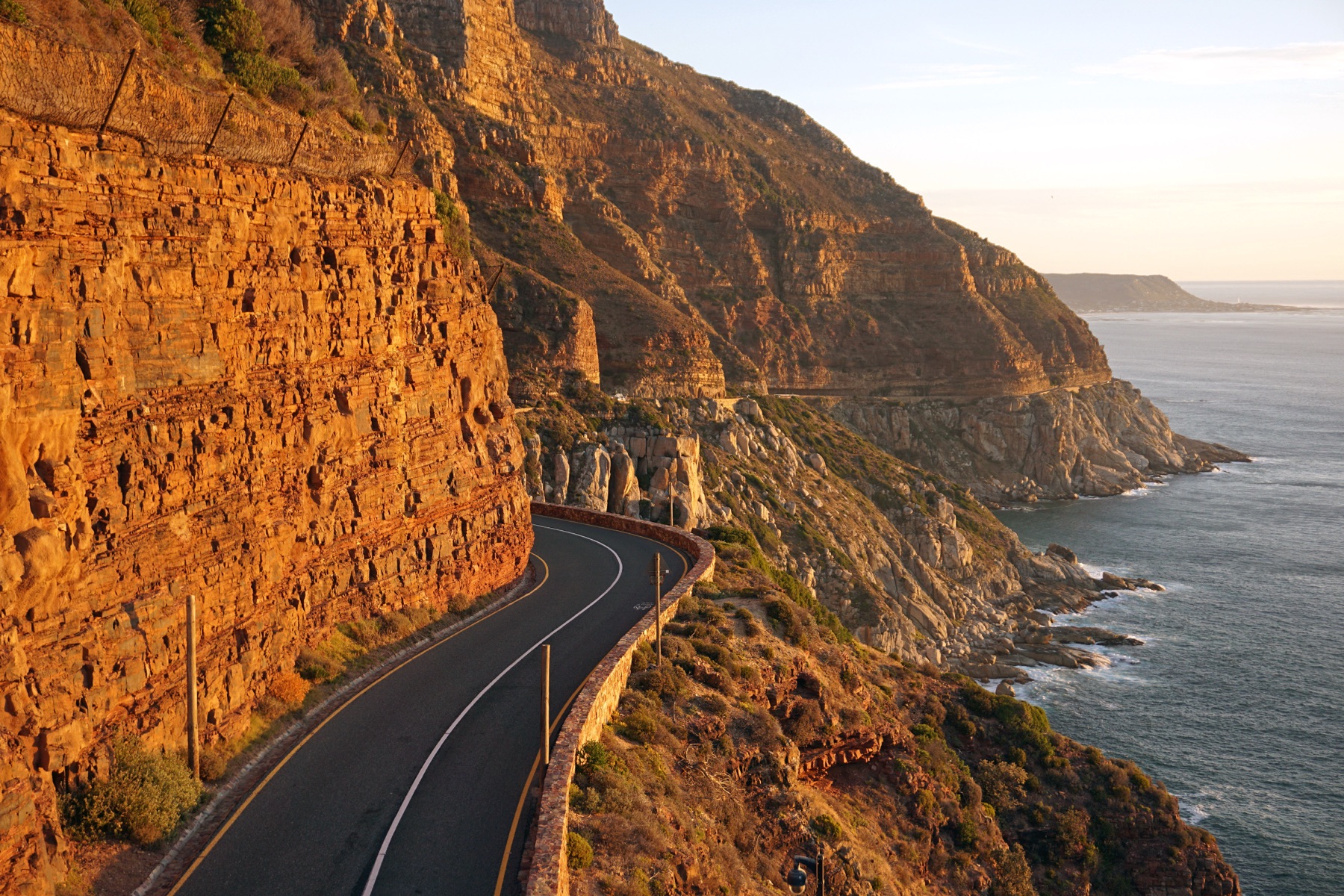 Chapman's Peak Drive curving along orange sandstone cliffs above the Atlantic at sunset